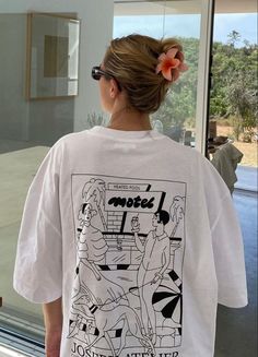 a woman standing in front of a window wearing a t - shirt that says motel