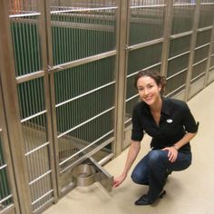 a woman kneeling down in front of a metal gate with bars on the sides and one hand