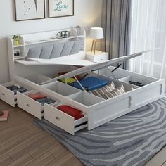 a white bed with drawers underneath it in a bedroom next to a window and rug