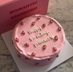 a pink birthday cake sitting on top of a table