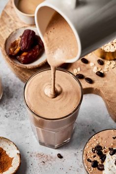 chocolate milkshake being poured into a glass with nuts and raisins on the side