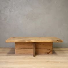 a wooden table sitting on top of a hard wood floor next to a gray wall