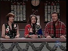 three people sitting at a table in front of a clock with christmas decorations on it