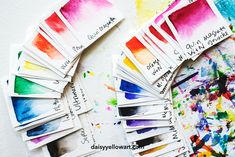 many different colors of watercolors are arranged on a white surface with one color swater in the middle