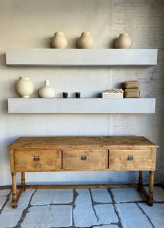 a wooden bench sitting in front of two shelves with vases on top of it