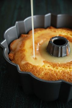 a bundt cake with icing being drizzled over it in a pan