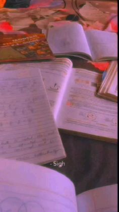 an open book sitting on top of a table next to other books and writing utensils