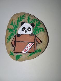 a painted rock with a panda in a box on it