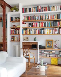 a living room filled with furniture and lots of books on the shelves in front of it