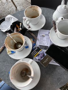 two cups of coffee sit on a table next to an ipad and other items that have been placed around it