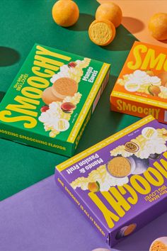 two boxes of cookies sitting on top of a green table next to some oranges