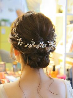 a woman wearing a bridal hair piece with flowers on it's head, in front of a bookshelf