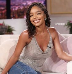 a woman sitting on top of a white couch in front of a tv screen and smiling