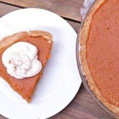 a slice of pumpkin pie on a plate next to a pie pan with whipped cream