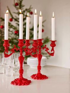 a red candelabra sitting on top of a table next to a christmas tree