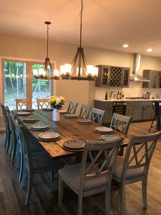 a dining room table with six chairs in front of an open kitchen and living area