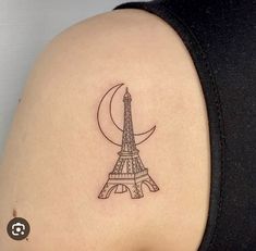 the back of a woman's shoulder with a small tattoo of the eiffel tower