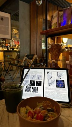 a bowl of food sitting on top of a table next to an open tablet computer