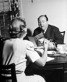 an old man and woman sitting at a table with tea cups in front of them