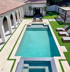 an aerial view of a swimming pool with lounge chairs in the foreground and grass on the ground