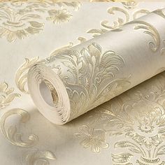 a roll of white and gold wallpaper next to a roll of toilet paper on top of a table