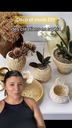 a woman is standing in front of some plants and vases with flowers on them