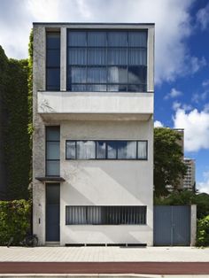 a white building with many windows and plants on the side of it's face