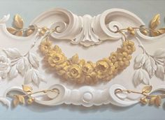 a painting of flowers and leaves on a white wall with gold trim around the edges