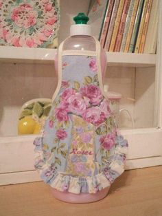 a pink and blue apron with flowers on it sitting in front of a book shelf