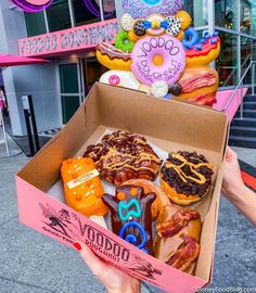 a box filled with lots of donuts on top of a street next to neon signs