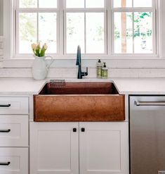 a kitchen sink sitting under a window next to a dishwasher