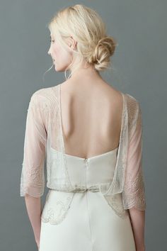 the back of a woman's wedding dress, with sheer sleeves and lace detailing