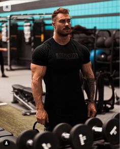 a man standing in the gym with his hands behind his back as he holds a barbell