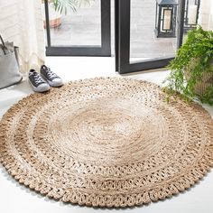 a pair of shoes sitting on top of a rug next to a plant in front of a door