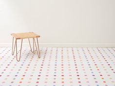 a small wooden table sitting on top of a white floor covered in multicolored dots