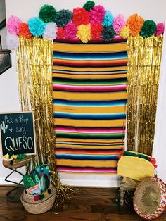 a mexican themed birthday party with pom poms on the wall and gold curtains