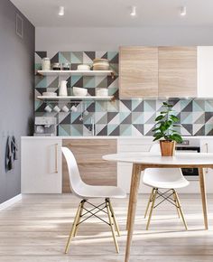 a table and chairs in a room next to a wall with geometric tiles on it