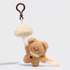 a brown teddy bear holding onto a white object with a hook on it's end