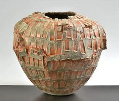 a vase that has been made out of clay and is sitting on a table with a white wall in the background