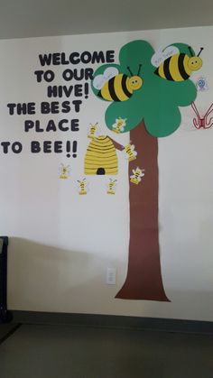 a welcome sign is hanging on the wall next to a tree with bees and honeybees