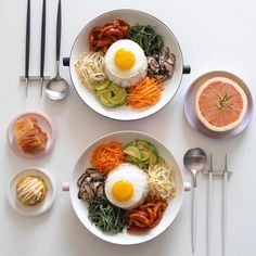 two white bowls filled with food next to utensils