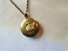 "A round brass locket with a swan on it is hanging from antiqued brass chain. The locket is a darkened brass and the swan is a made of raw brass giving it a golden color. You can select your length of chain at checkout. Locket measures approx. 1\" and opens to hold two small pictures. Necklace will come in a gift box and bow ready for gift giving. Enter back into store: rhondastreasures.etsy.com   RhondasTreasures" Swan Locket, Ruby Locket, Swan Jewelry, Swan Necklace, Neck Jewellery, Small Pictures