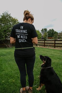 a woman in black shirt standing next to a dog