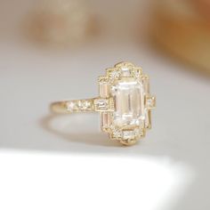 an oval cut diamond ring with baguettes set in yellow gold setting on a white surface