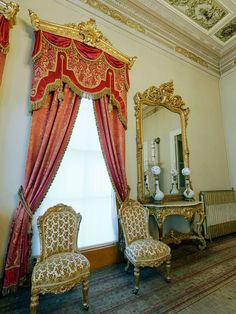 an ornately decorated room with two chairs and a mirror
