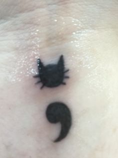 a small black cat tattoo on the side of a woman's chest and neck