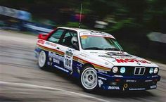 a white and blue car driving down a road next to trees in the background,