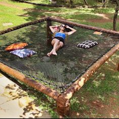 a woman laying in a hammock made out of wood and netting on the grass