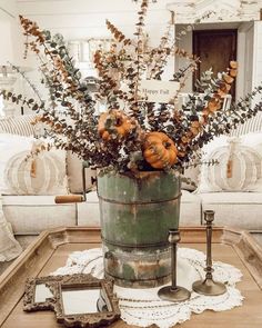 a metal bucket filled with pumpkins on top of a wooden table next to pillows