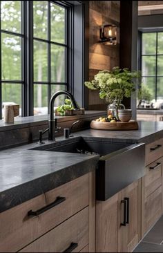 a kitchen with wooden cabinets and black counter tops, along with a large window over the sink